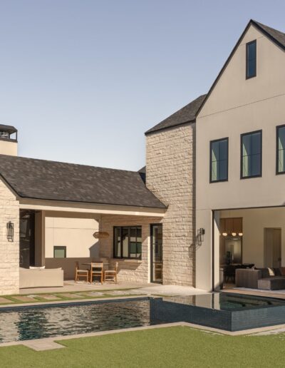Modern house with stone exterior, large windows, and a small swimming pool in the backyard patio area, with outdoor seating and manicured landscaping.